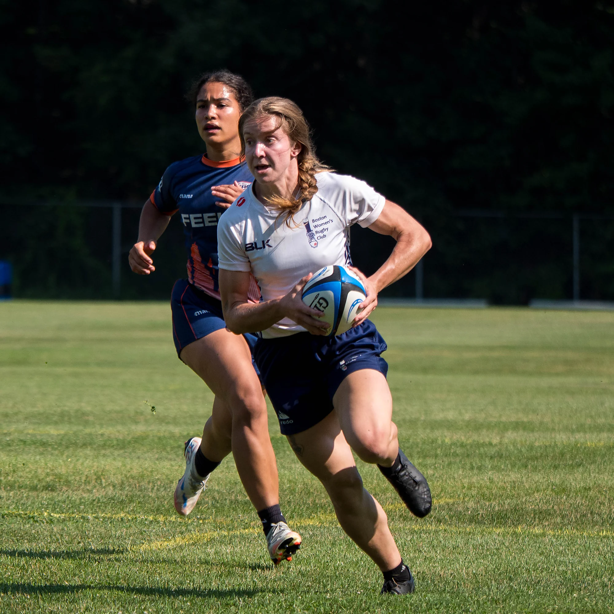 Boston Women's Rugby Club ball carrier breaks clear with an NYRC defender in chase — women's premier