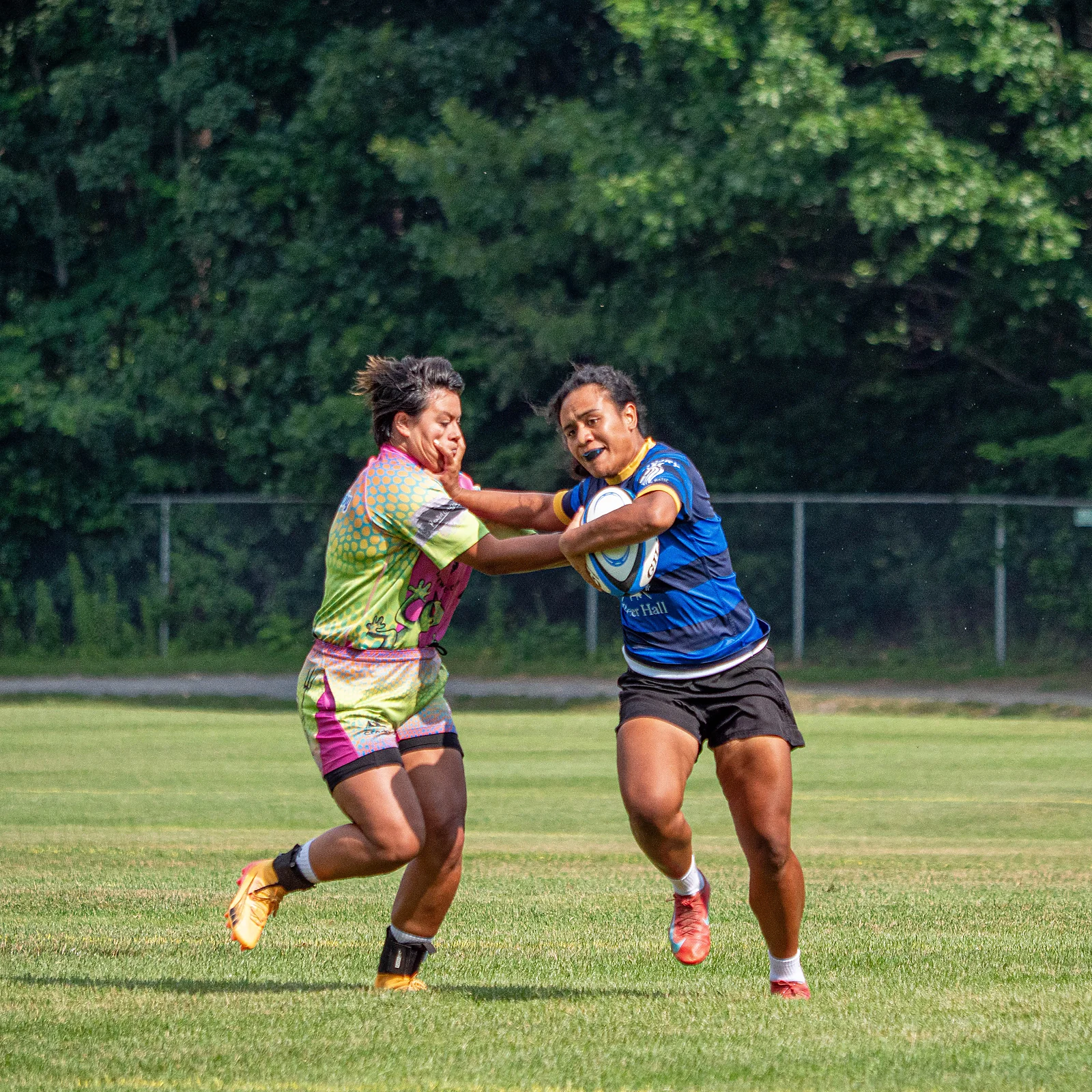 Ball carrier fends off a defender at full stride — women's social